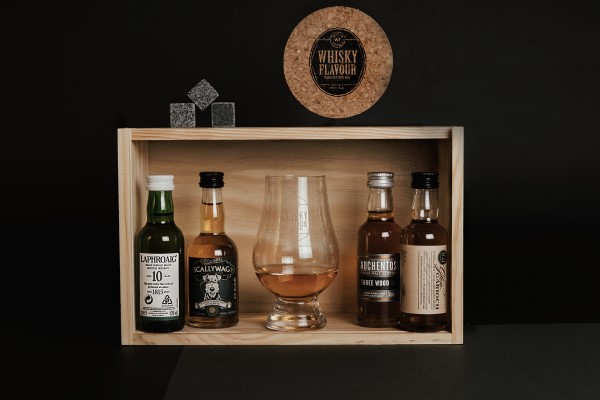 Miniaturas de whisky con un vaso de whisky, cubos y un portavaso en una caja de maderas