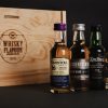 4 expresiones de whisky miniatura cerca de una caja de madera